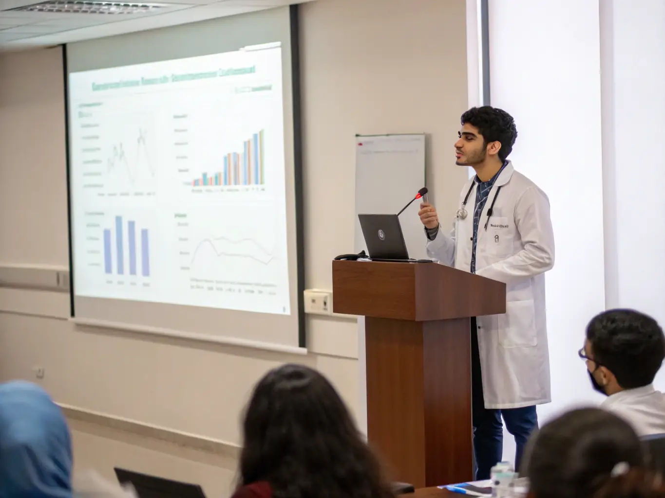 A video still from a recorded lecture featuring a renowned oncologist discussing the latest advancements in cancer treatment, set in a modern conference room.